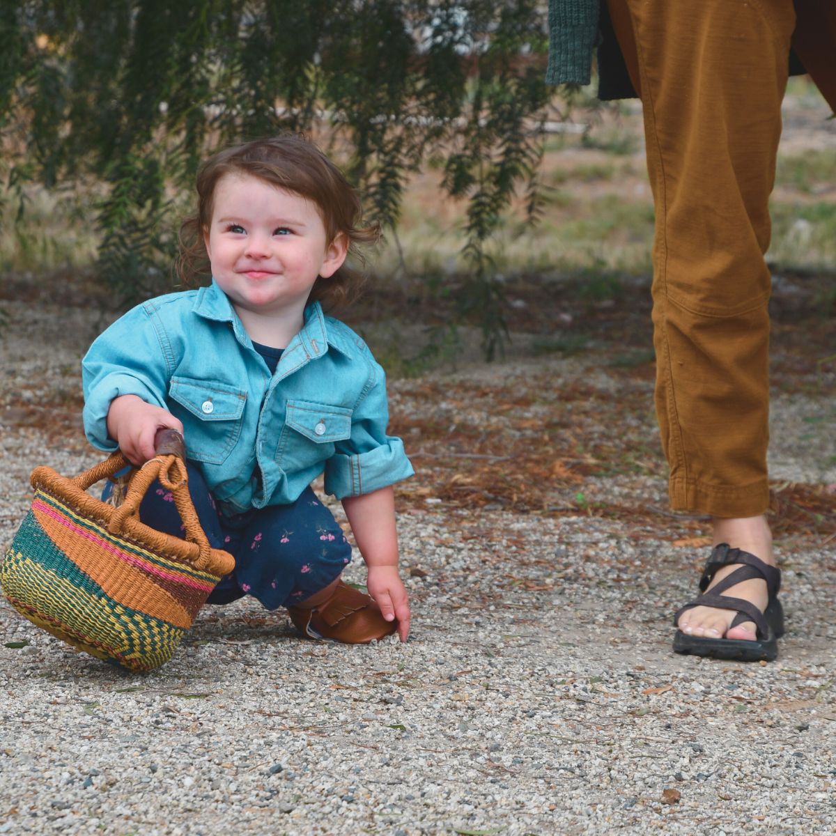 Baby squatting touching shoe holding basket near mom