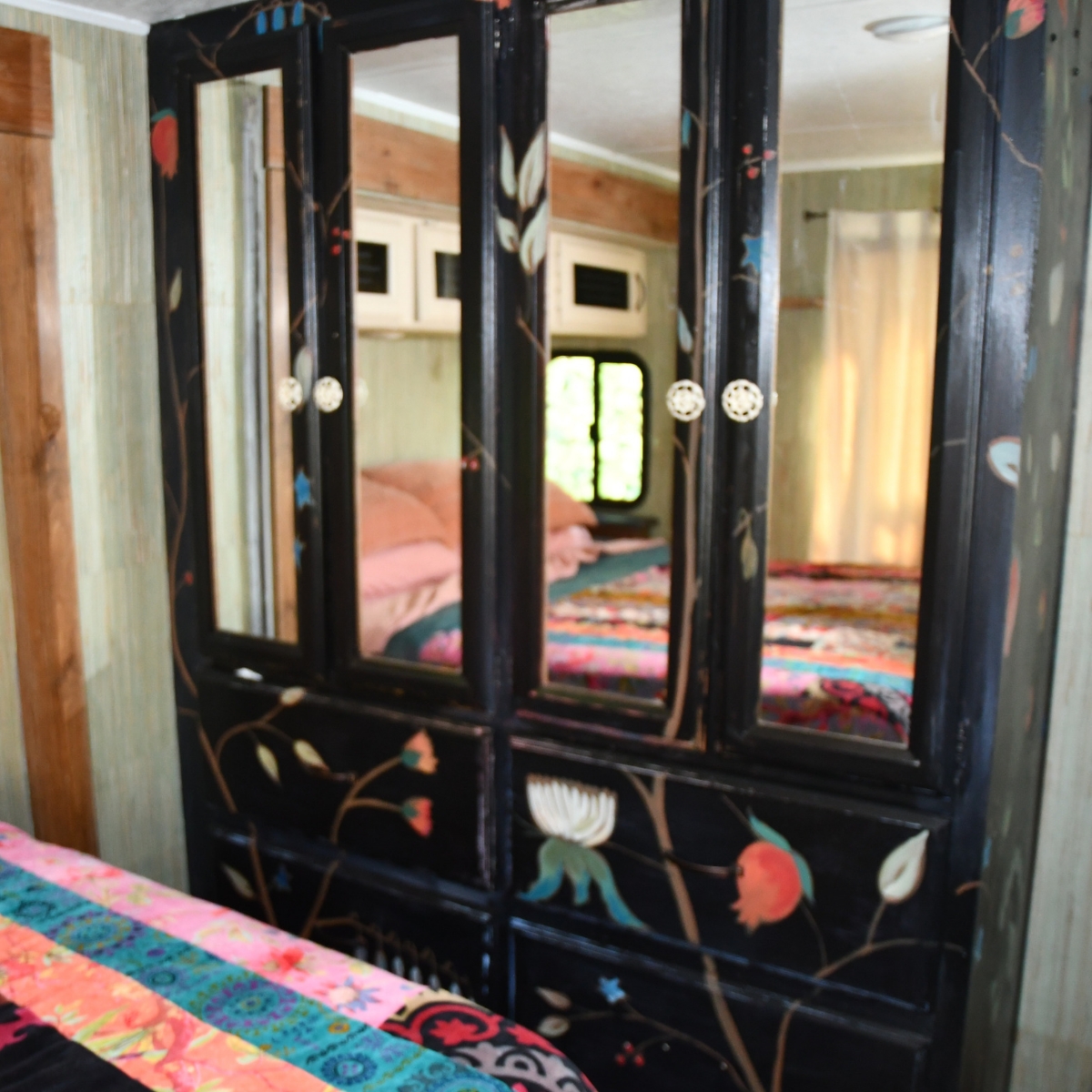 black built in closet painted to look like freestanding black armoir with painted bohemian style flowers and branches