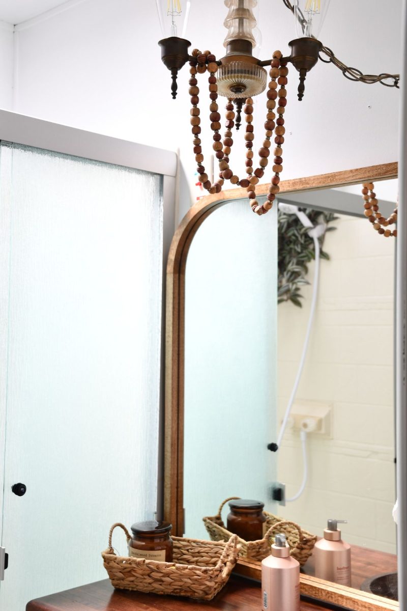 vintage light chandelier with vintage style light bulb hanging over sink with strand of wooden beads draped on