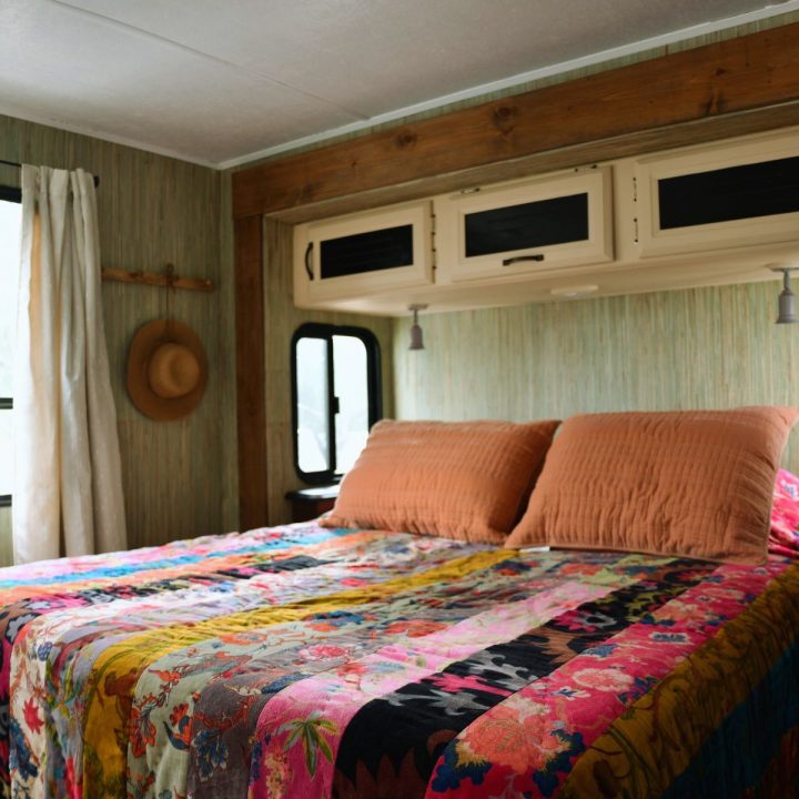 cotton velour comforter multi patterened on queen bed in travel trailer. wall paper and wood stained trim.