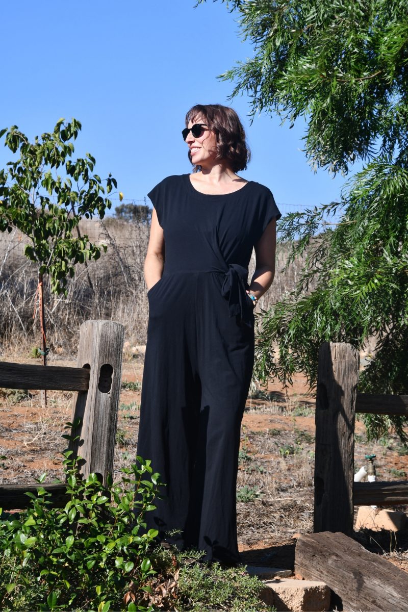 Woman wearing black cotton Jumper, capped sleeves with black tie on the side and black sunglasses.